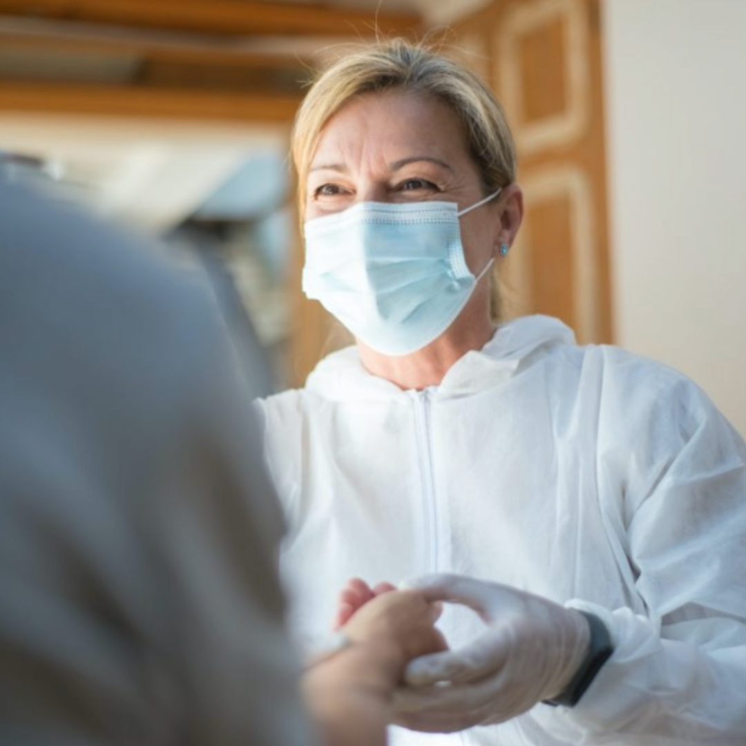 Female Nurse smiling while holding patient hand